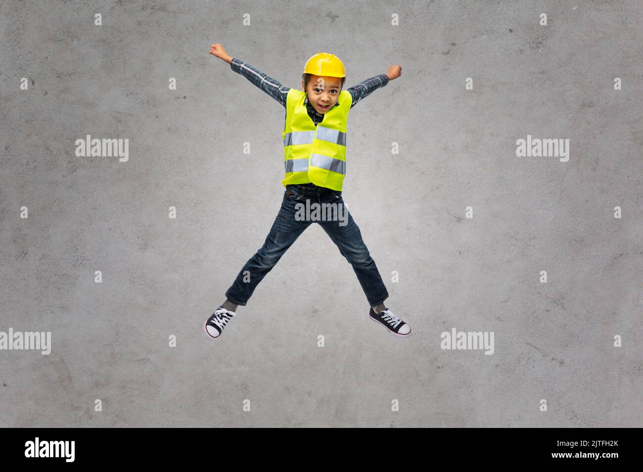 boy in safety vest and construction helmet jumping Stock Photo Alamy