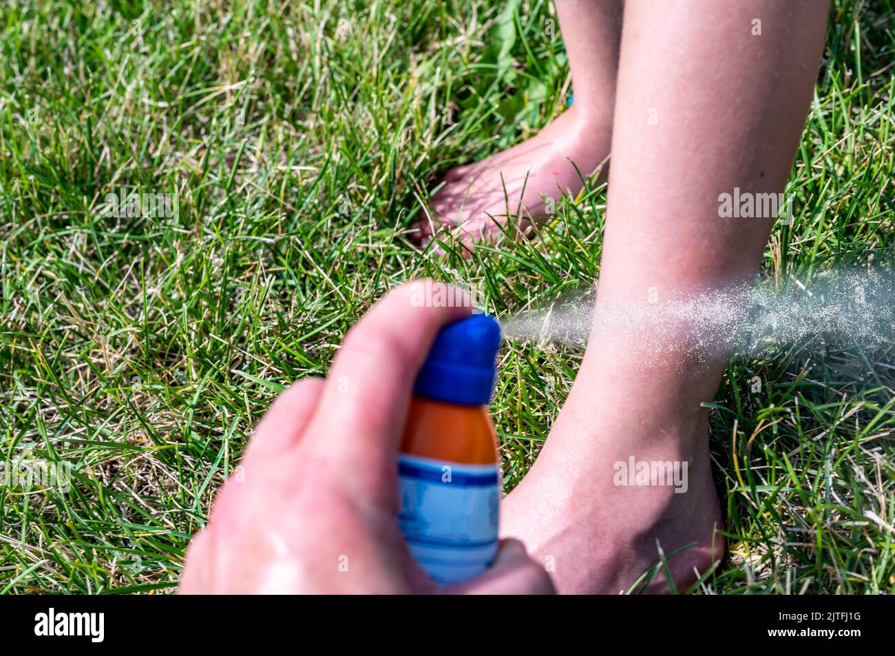 Applying an aerosol spray sunscreen to a young child in the summer