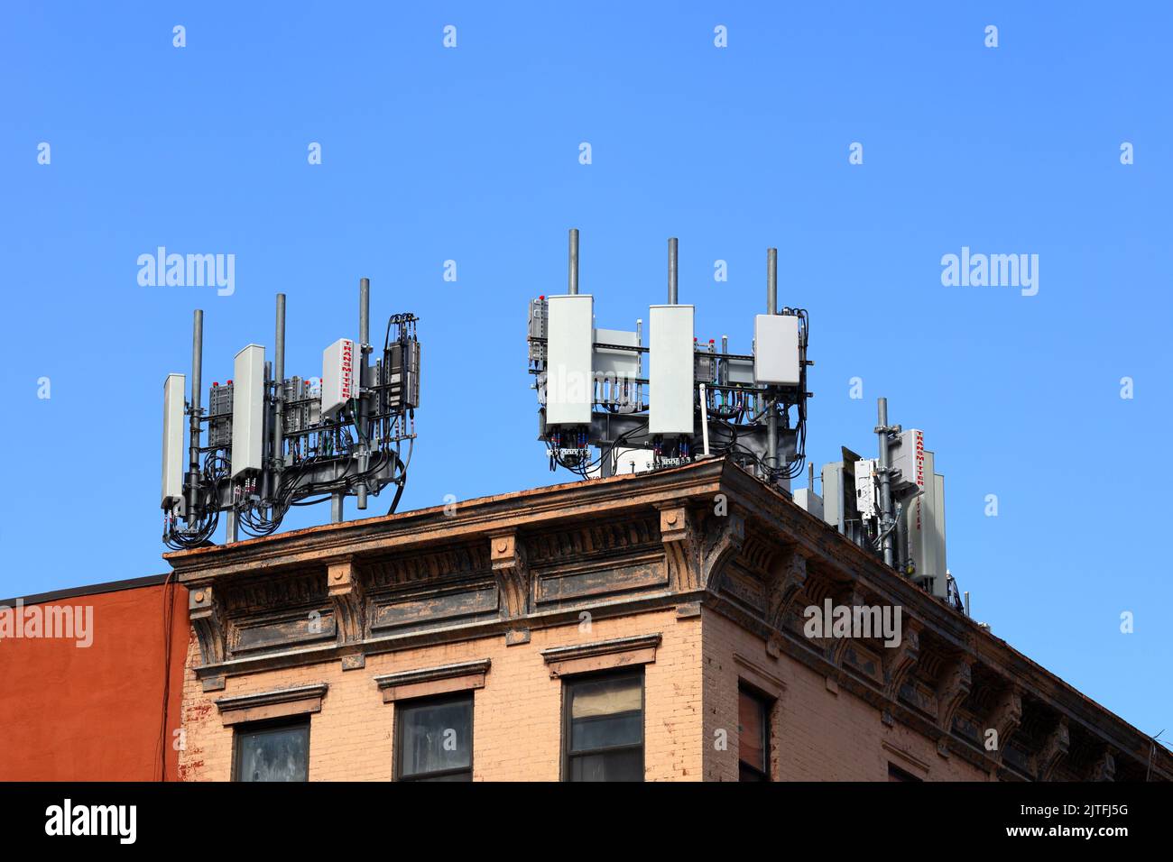 Mobile telecommunications equipment on a rooftop with LTE 4G 5G network transmitters, wifi, wireless, other cellphone antennas, and infrastructure Stock Photo