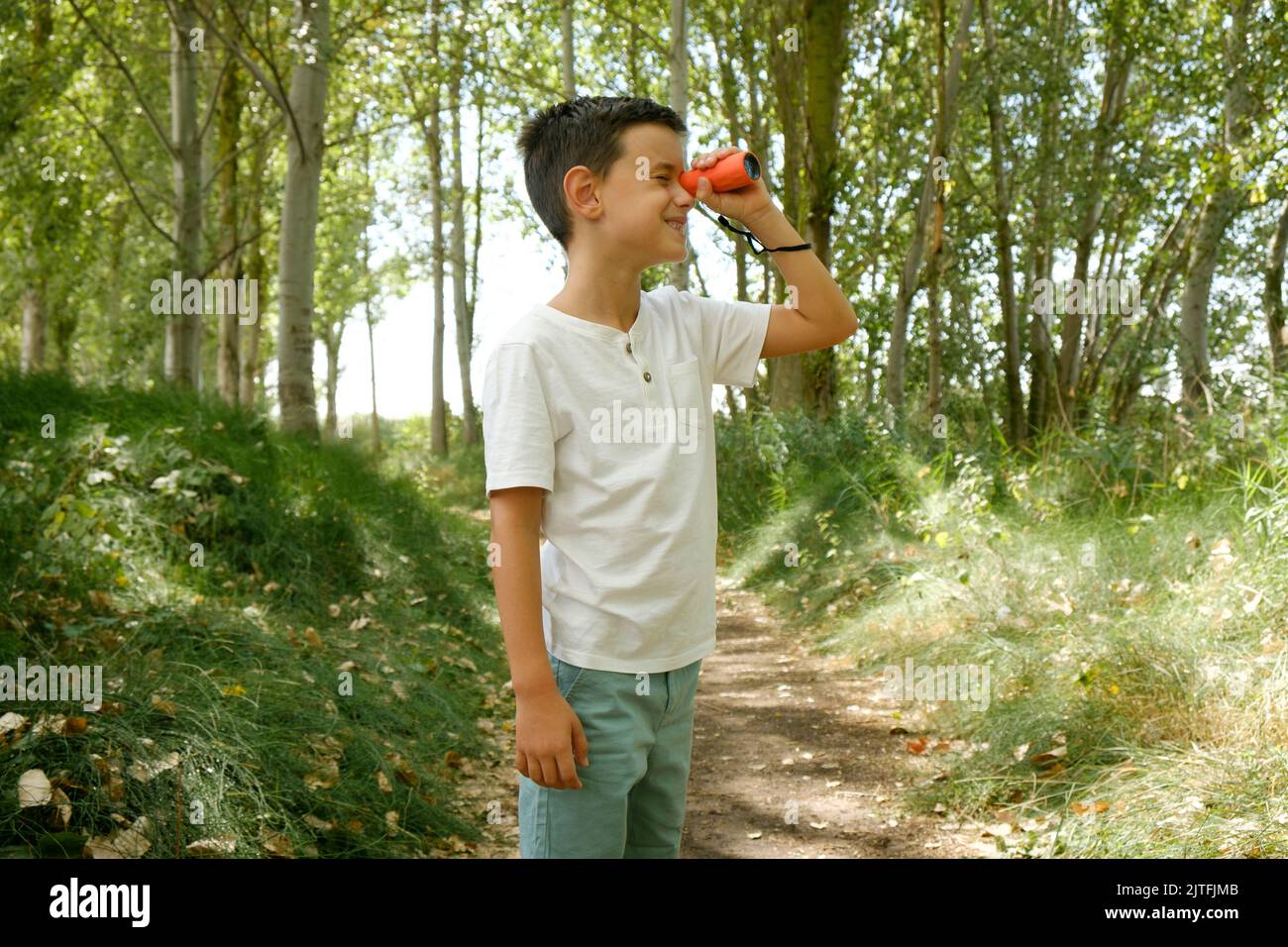 child looks through a monocle in nature. Outdoor activities in childhood Stock Photo