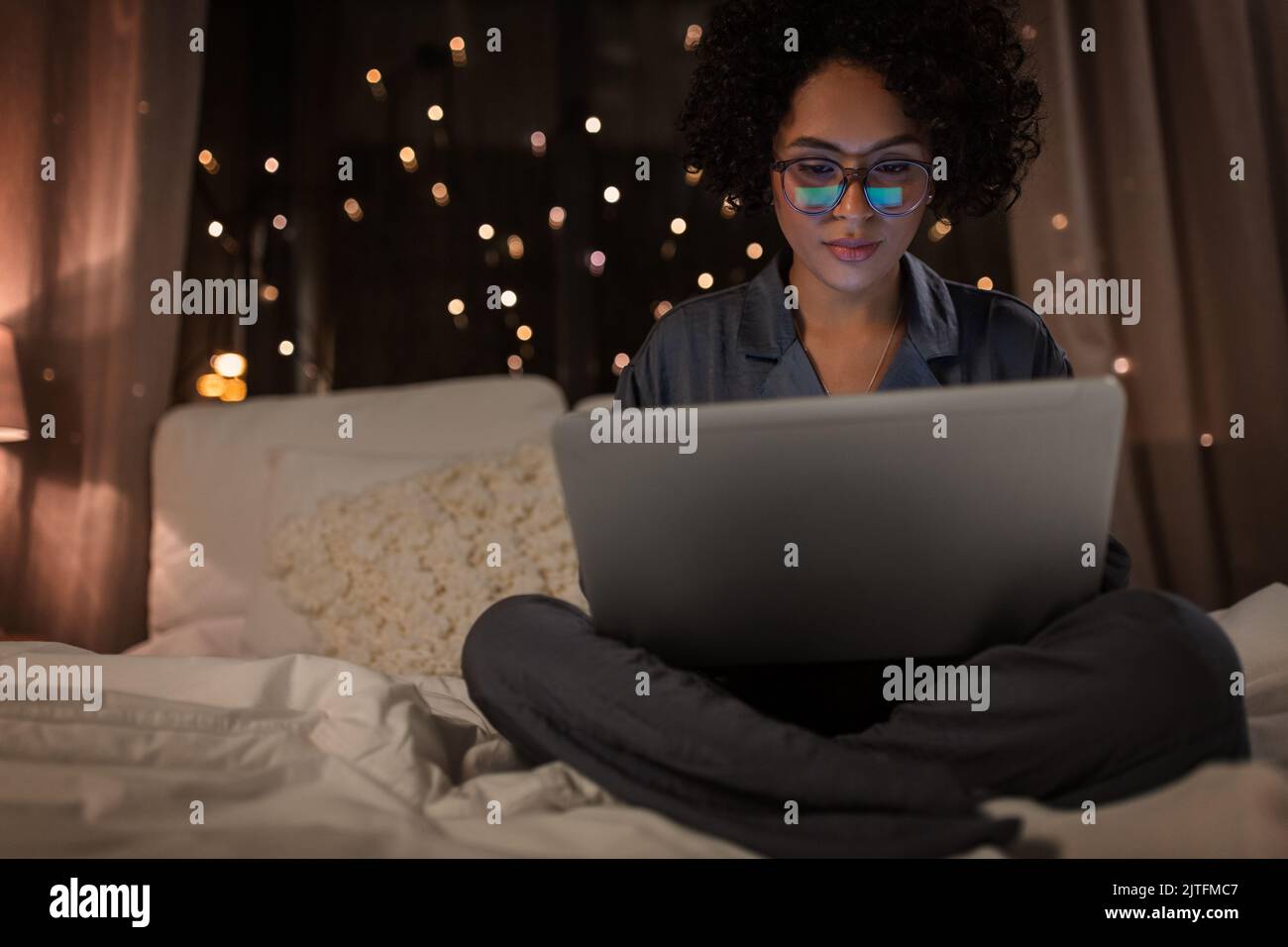 woman with laptop working in bed at night Stock Photo