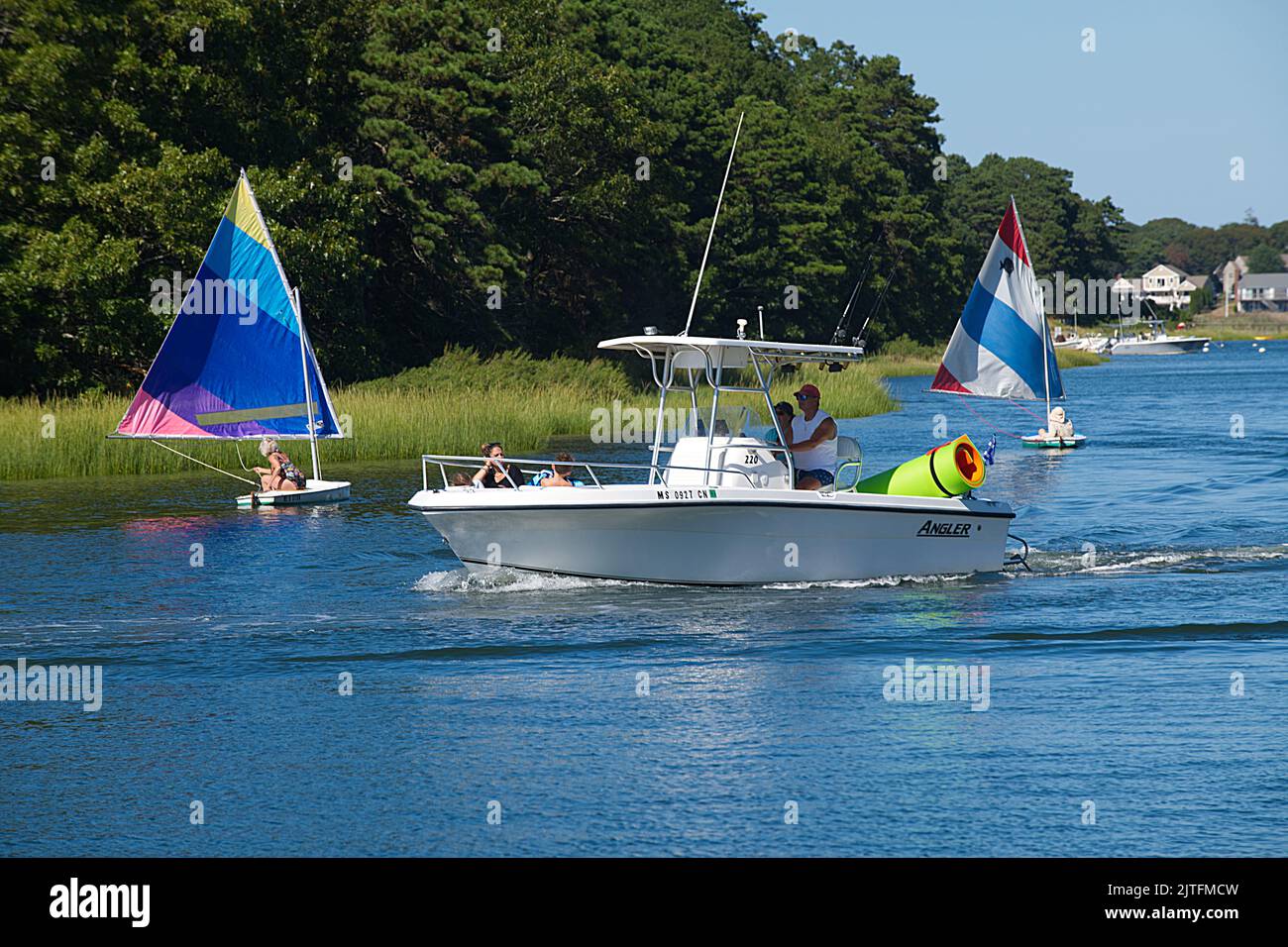 A motorboat passing two sail boats on the Bass River in Dennis, Massachusetts, on Cape Cod, USA Stock Photo