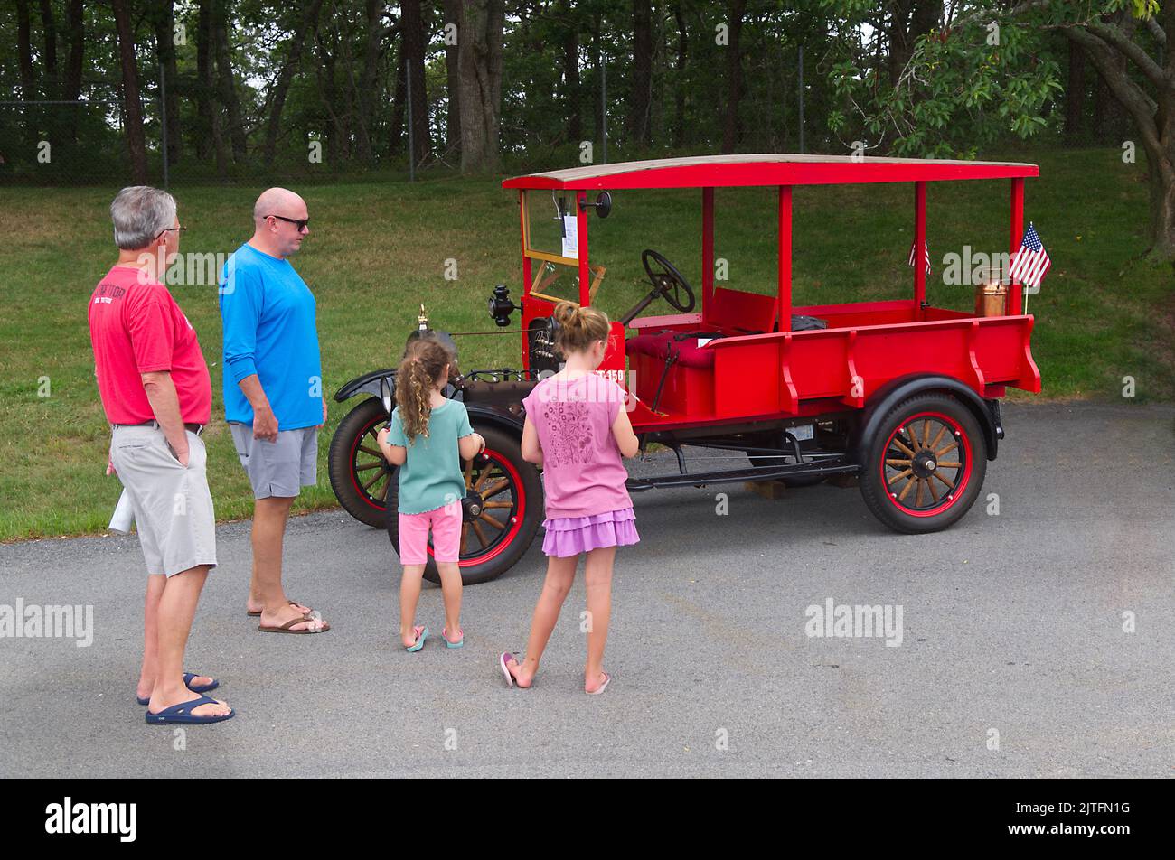 A family group looks over a 1925 Ford Depot Hack on display at a vintage car show in Dennis, Massachusetts on Cape Cod Stock Photo