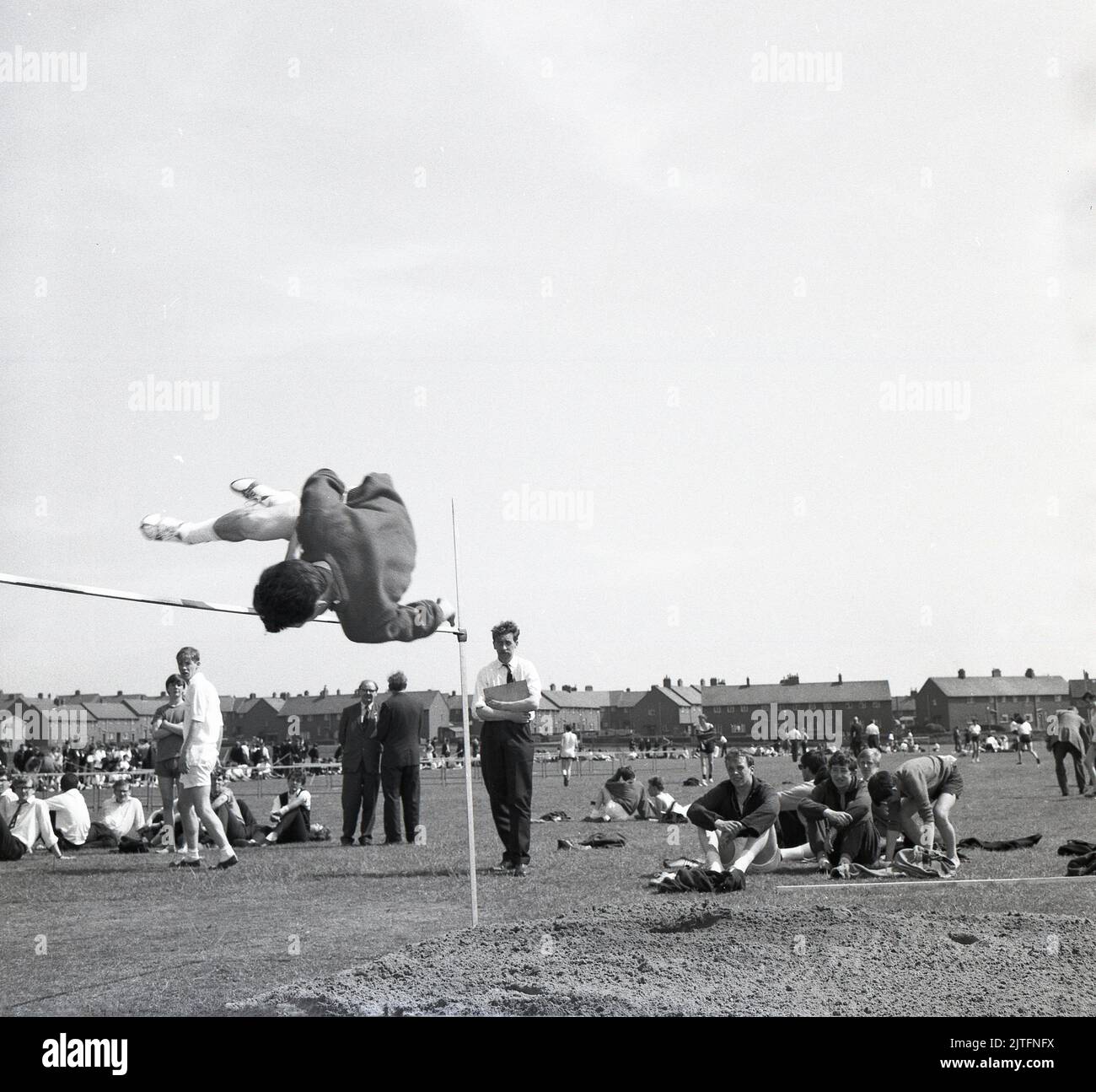 1960s, historical, school sports, a boy doing the high jump, clearing