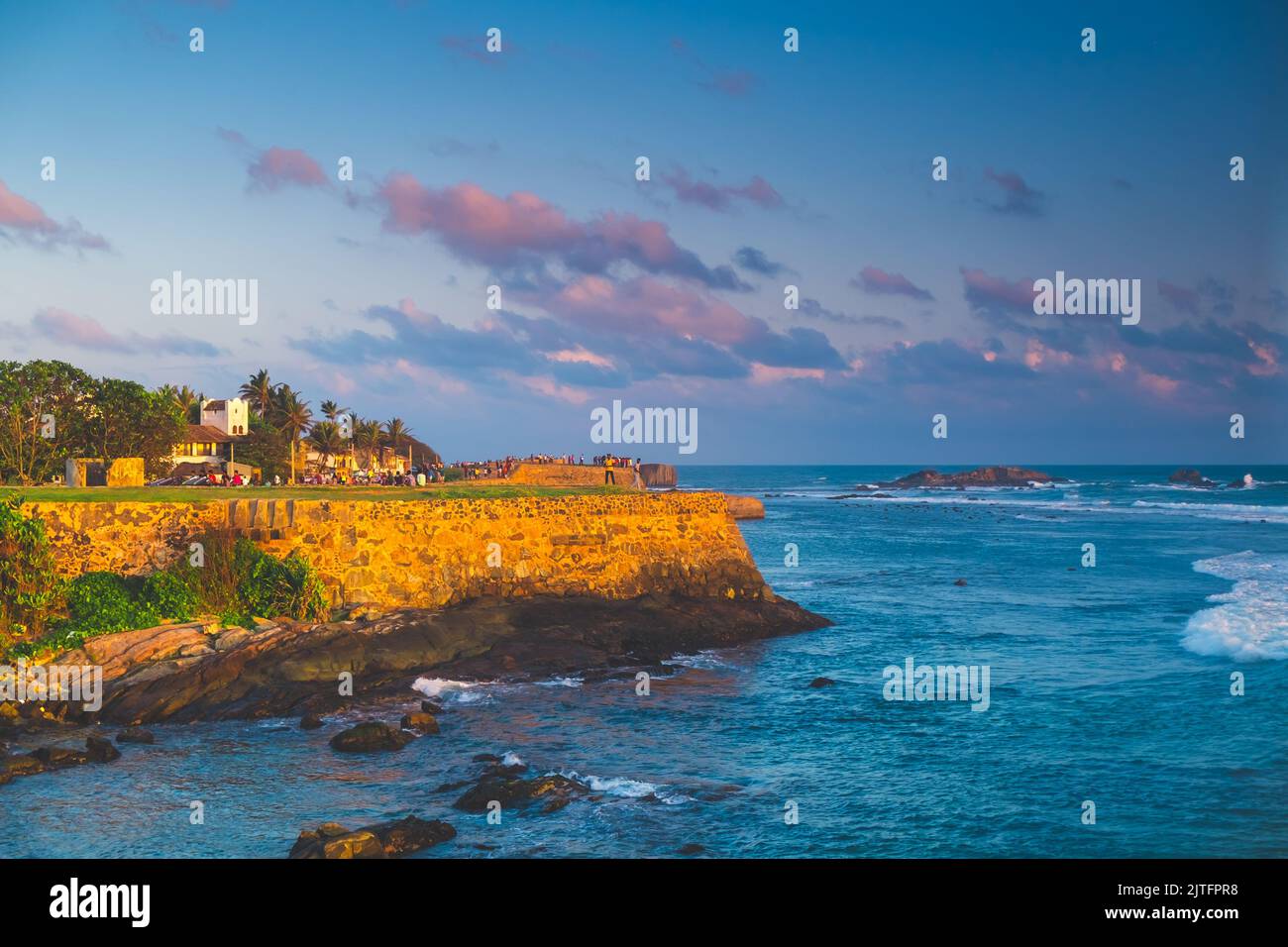 Galle Fort panorama with old walls in sunset orange light against blue sky with pink clouds, ocean in background. Largest city fortress and port of Sri Lanka - popular tourist destination. Stock Photo