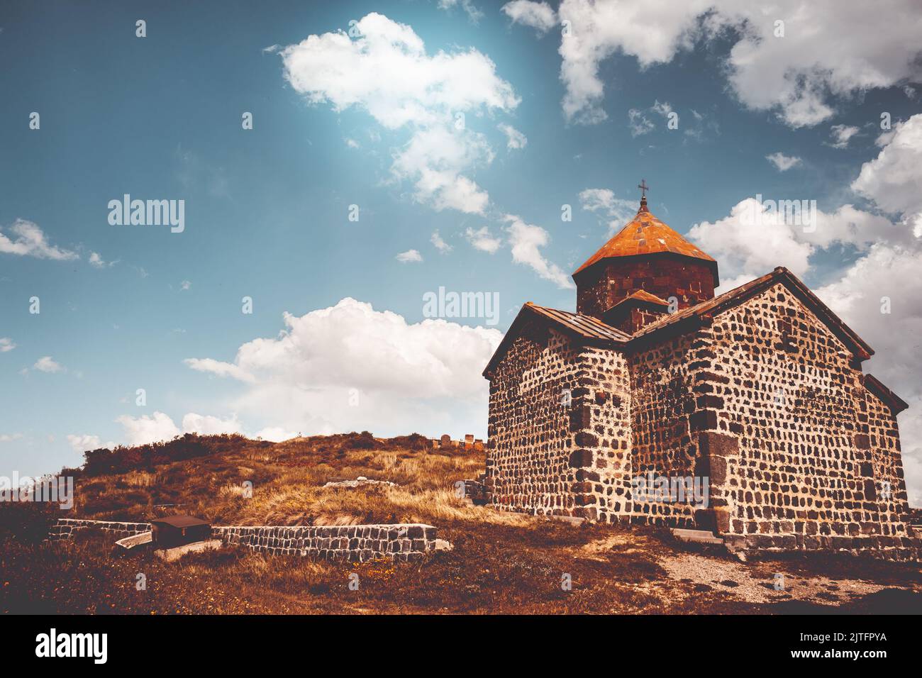 Ancient chapel in Armenia. Tourism and traveling destination. Old stone church of S. Karapet part of the Sevanavank monastery, Lake Sevan. Best famous travel location. Retro vintage orange tone filter Stock Photo