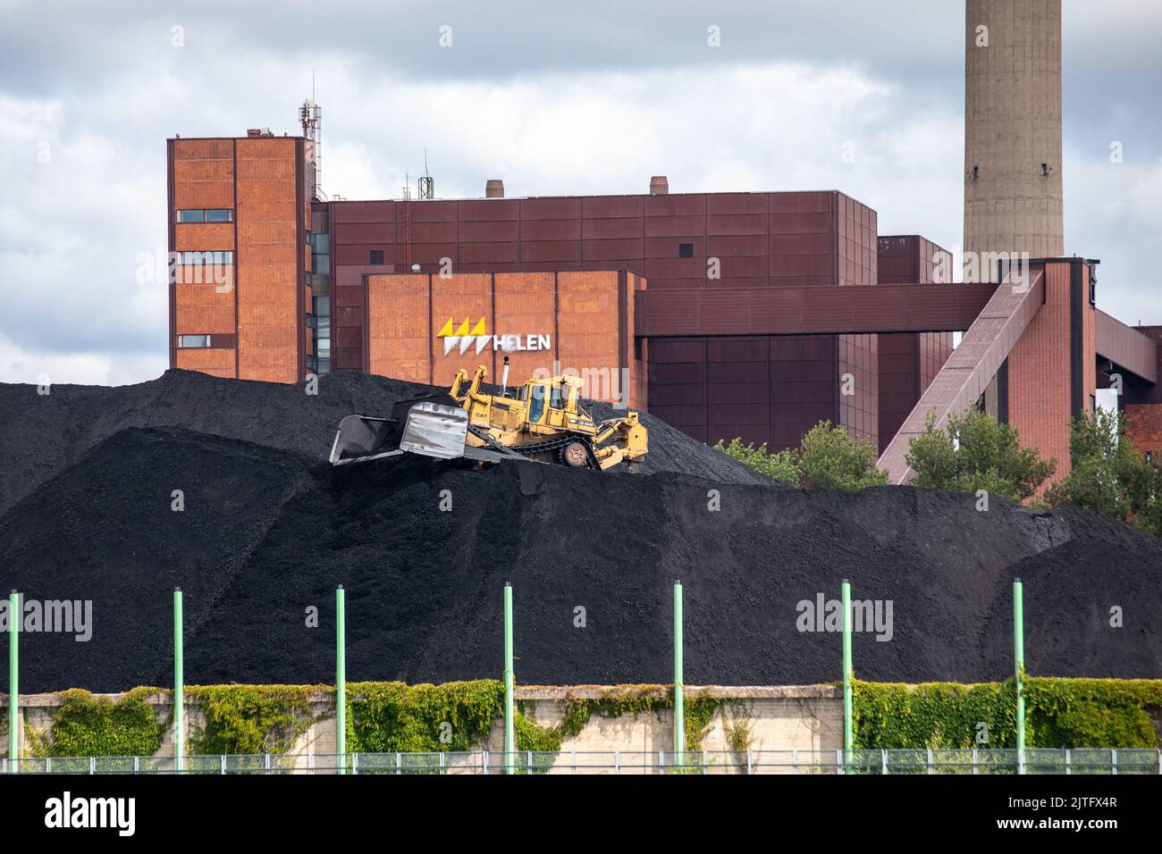 Yellow bulldozer piling Helen's Hanasaari power plant coal stock in Helsinki, Finland Stock Photo