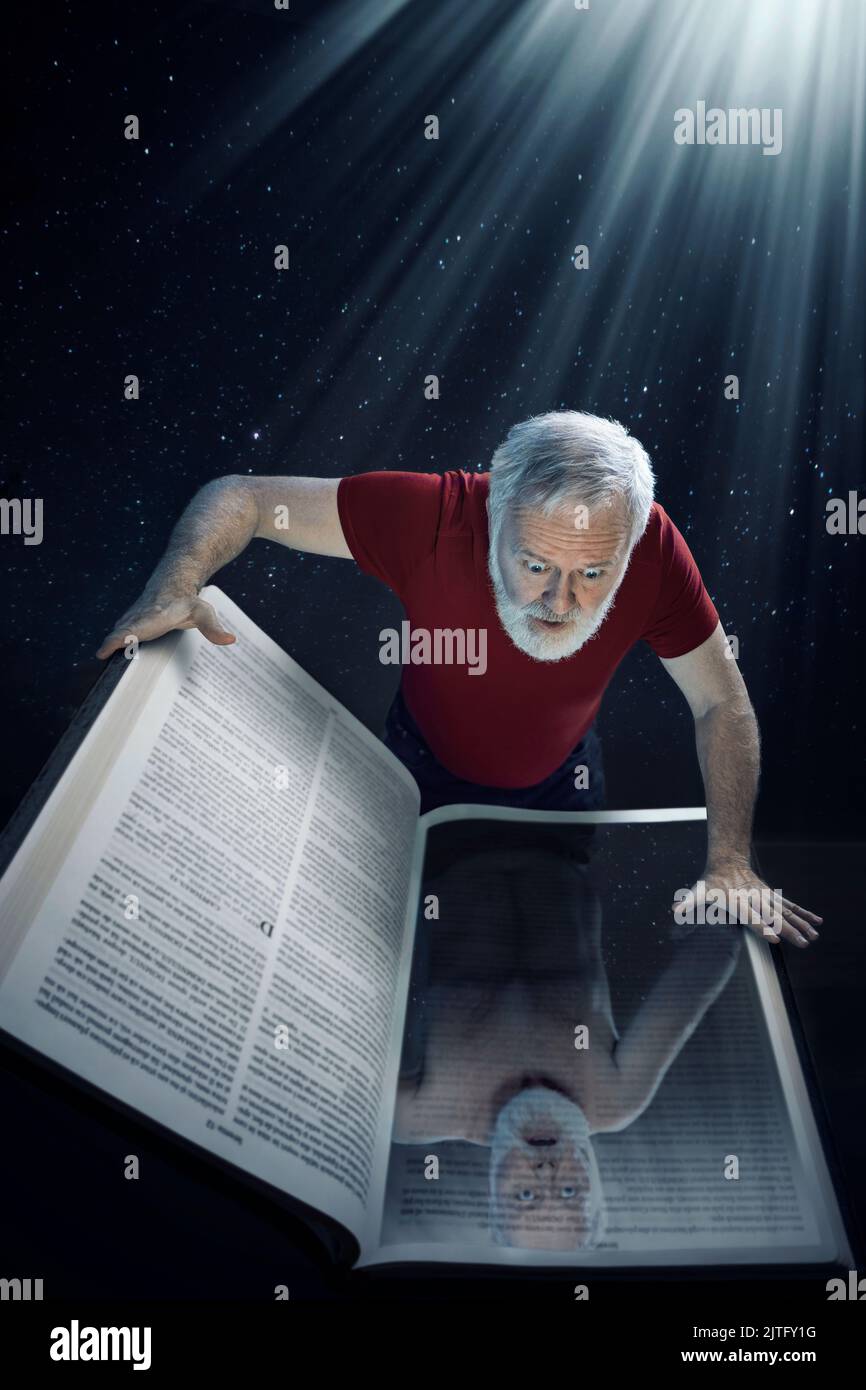A mature man looking into the Holy Bible and seeing himself as he is undressed. Concept for looking into the Holy Bible to see who I am in the light o Stock Photo