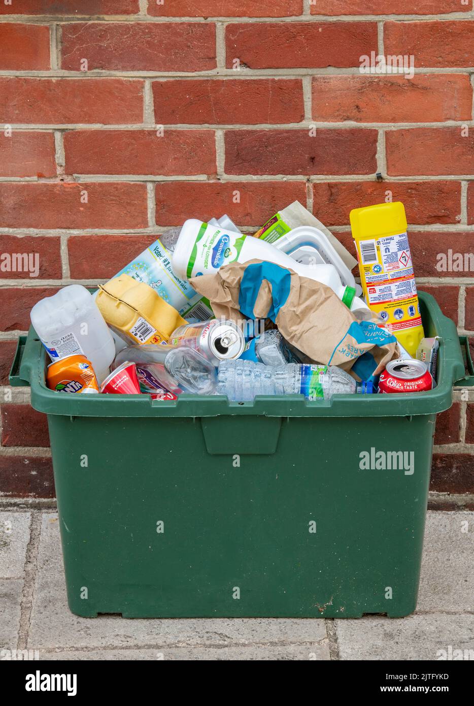 green recycling bin full of papers, cards and plastics with glass