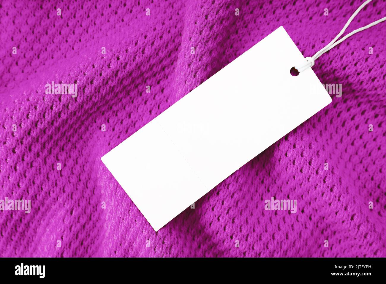 White blank rectangular clothing tag, label mockup template on purple