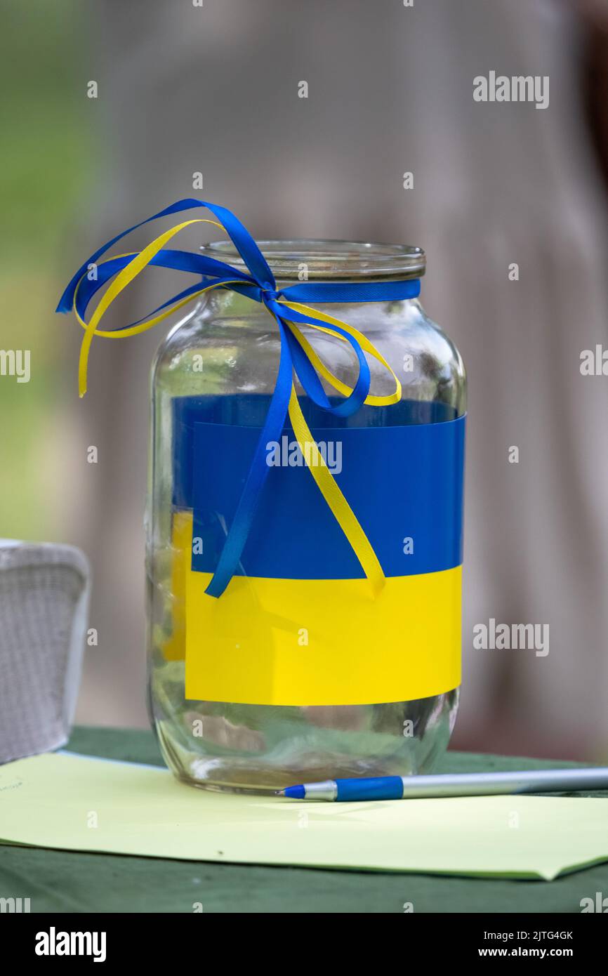 Donation jar. Charity event. Aid to Ukraine. Blue-yellow Ukrainian flag. Collection of funds for needs. The nation helps the Ukrainian army. Stock Photo