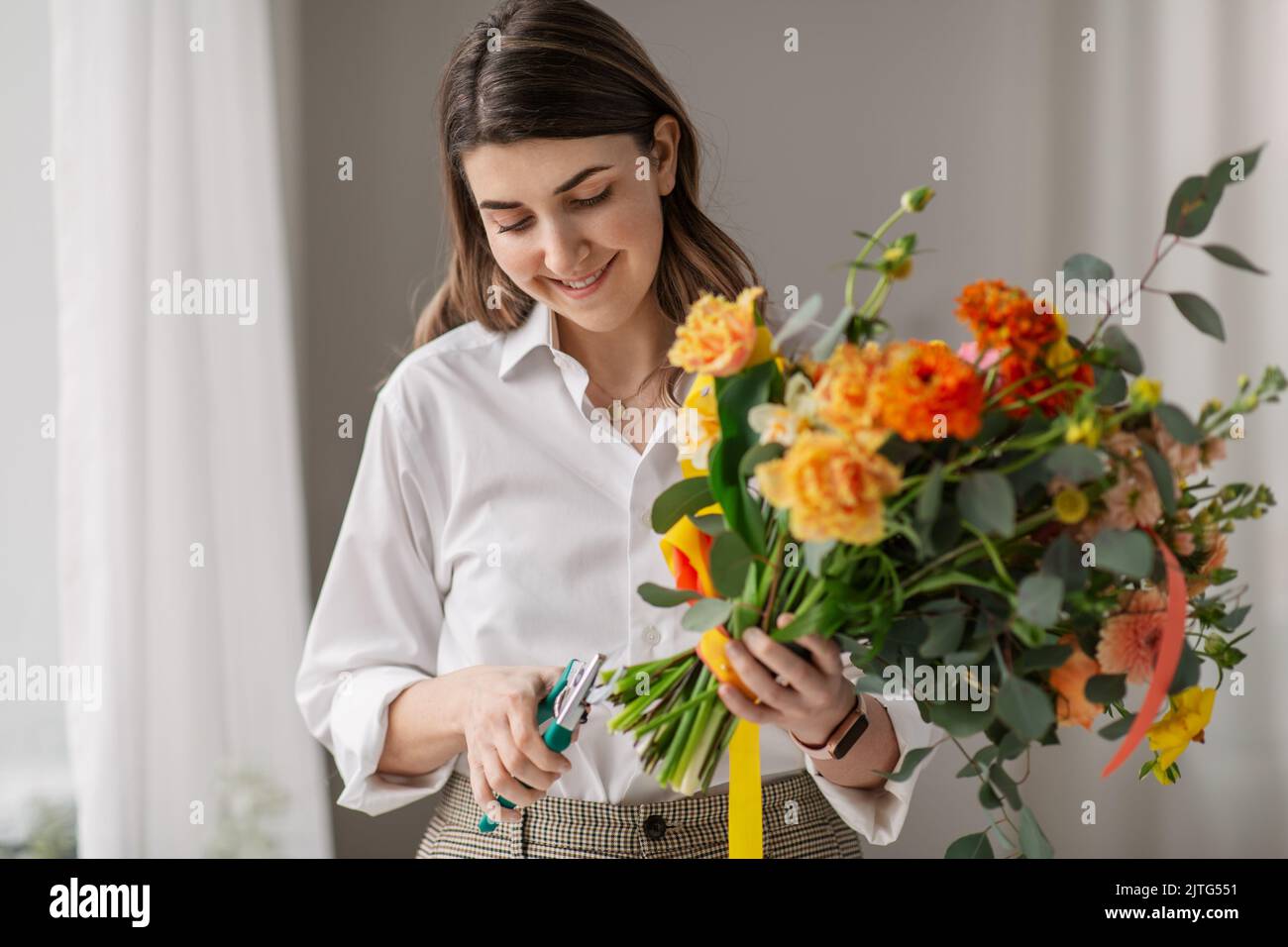 happy woman making bunch of flowers at home Stock Photo