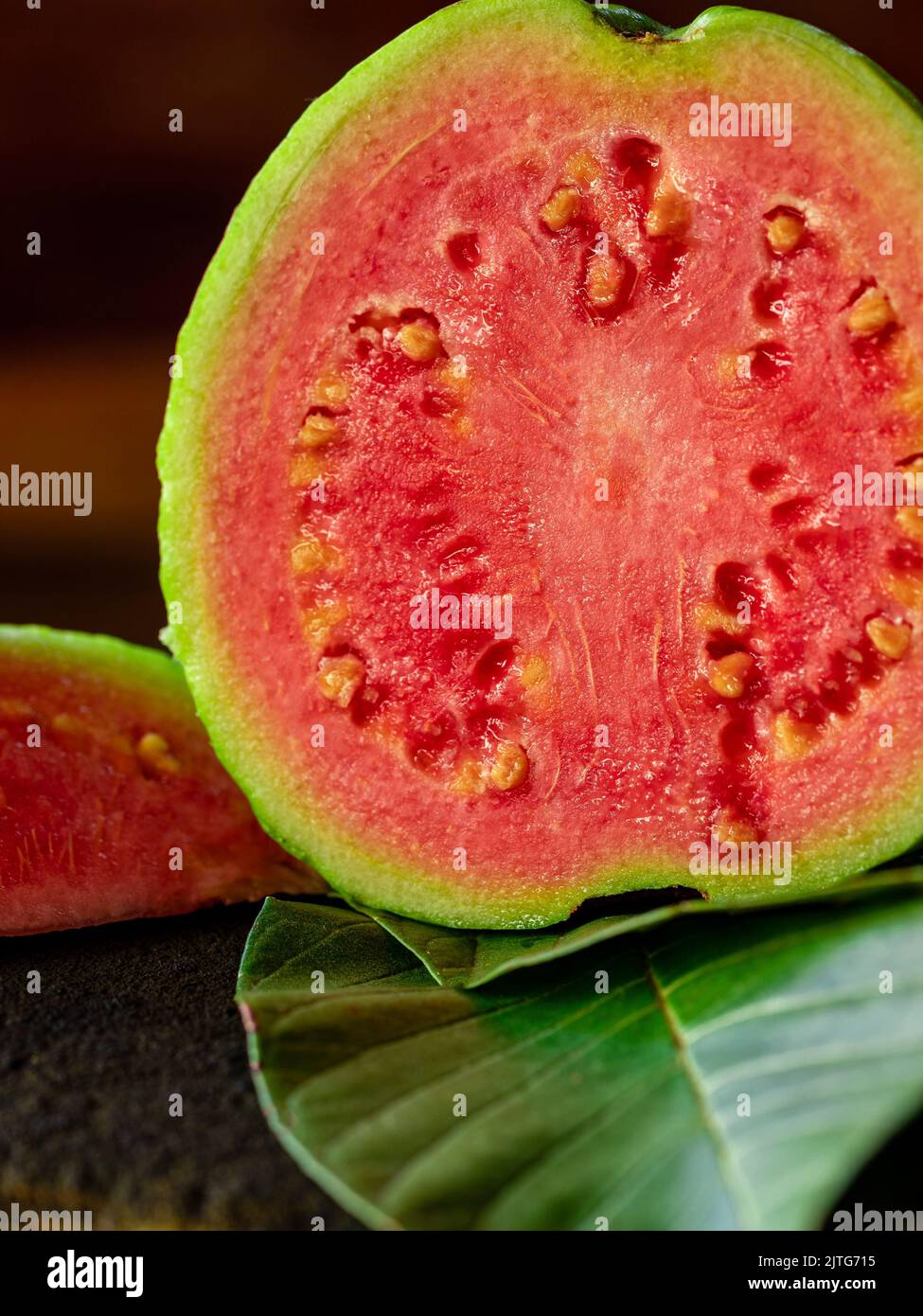 Fresh red guavas with green leaves on wooden demolition background