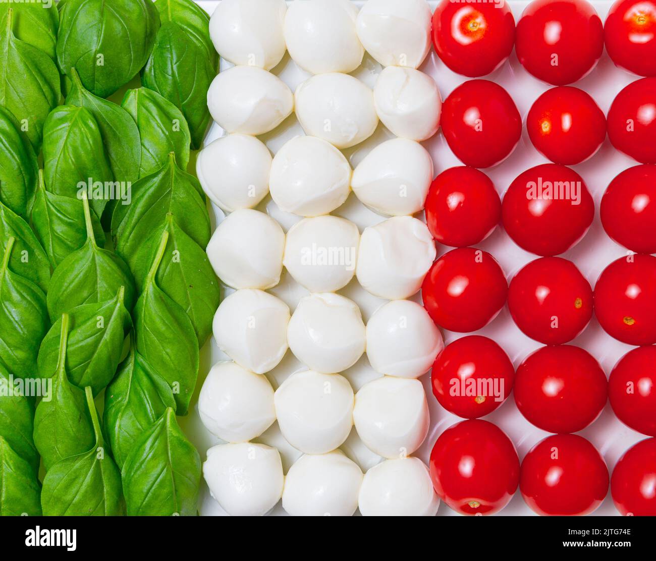 Italian flag made of organic basil, mozzarella cheese and cherry tomatoes on a white background. Advertisement for traditional Italian and Mediterrane Stock Photo