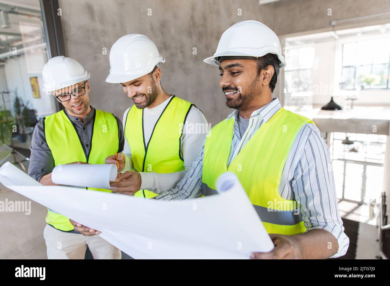 architects in helmets with blueprint at office Stock Photo