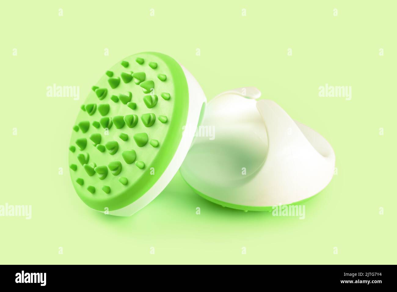 Hand massager with silicone spikes for anti-cellulite massage procedure isolated on green background. Massage brush tool for problem body zone, self-c Stock Photo