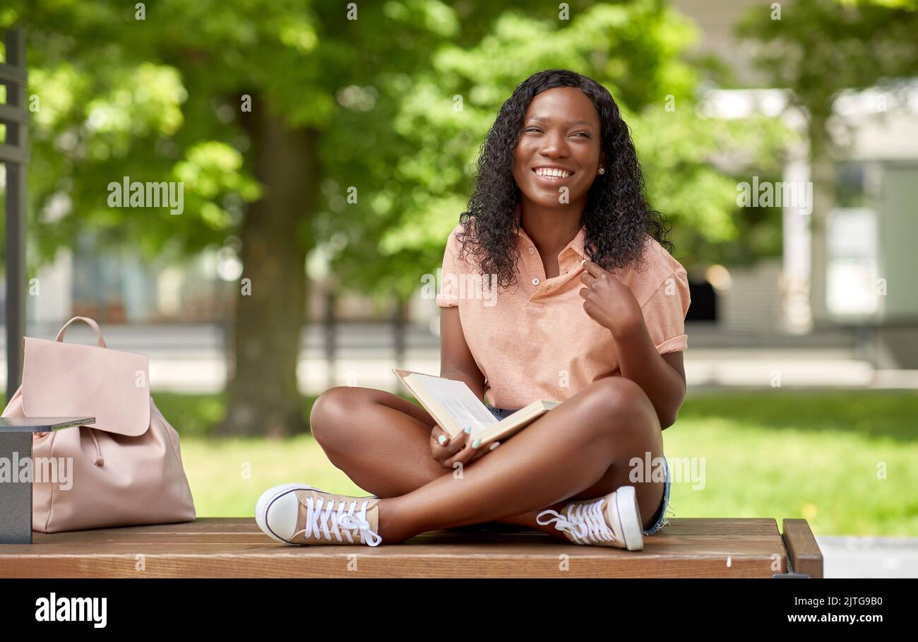 happy african student girl reading book in city Stock Photo - Alamy