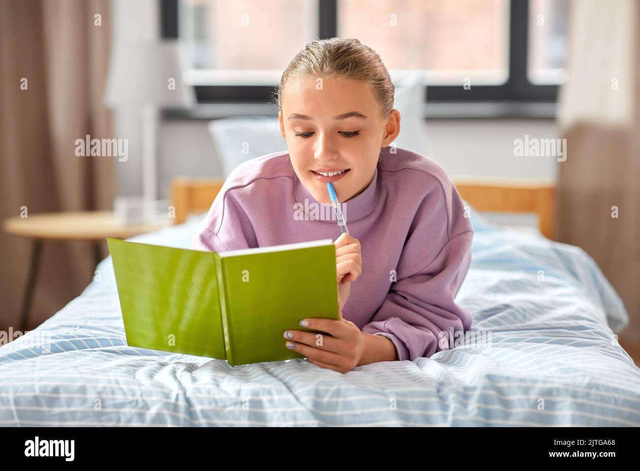 thinking girl with diary lying on bed at home Stock Photo