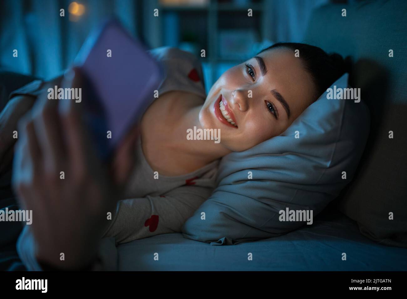 teenage girl with phone lying in bed at night Stock Photo Alamy