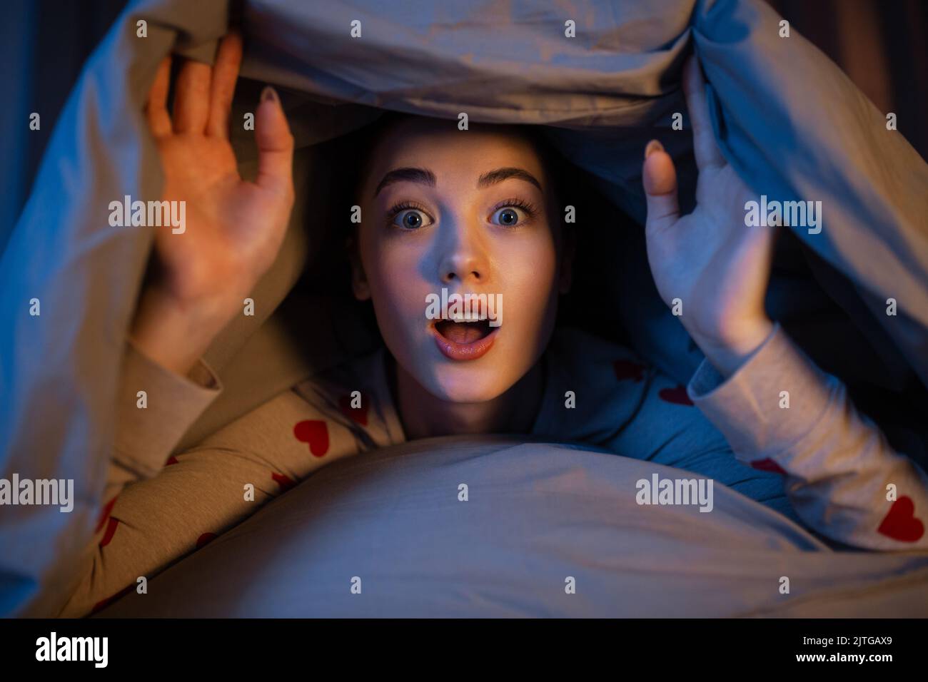 surprised teenage girl under blanket in bed Stock Photo Alamy