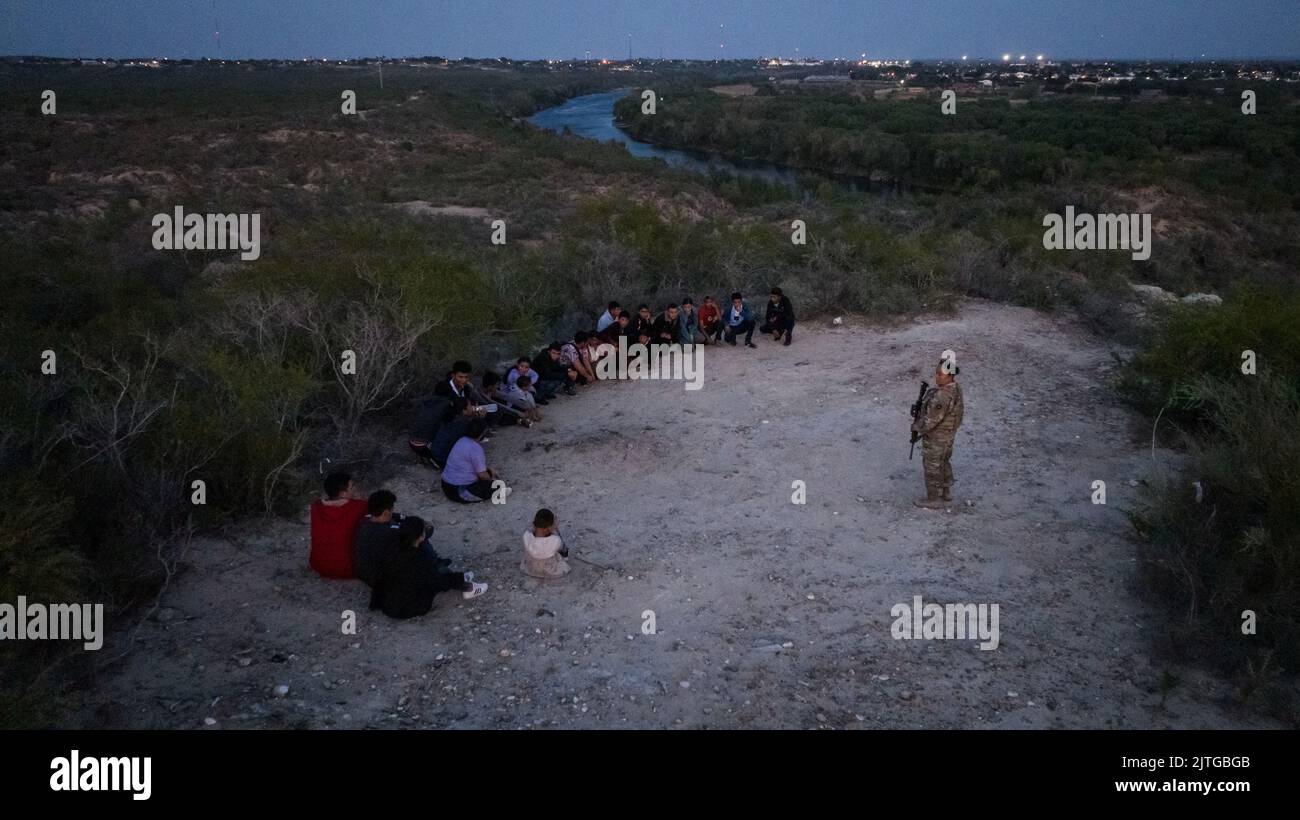 A member of the Texas Army National Guard stands near asylum-seeking migrants after they crossed the Rio Grande river into Roma, Texas, U.S., August 29, 2022.  REUTERS/Adrees Latif Stock Photo
