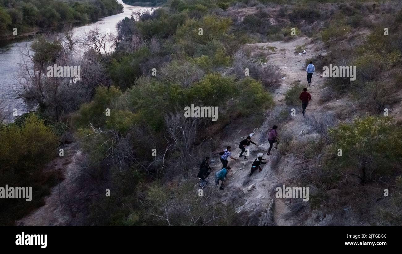 Asylum-seeking migrants climb a hill as they navigate a migrant trail after being smuggled across the Rio Grande river into Roma, Texas, U.S., August 29, 2022.  REUTERS/Adrees Latif Stock Photo