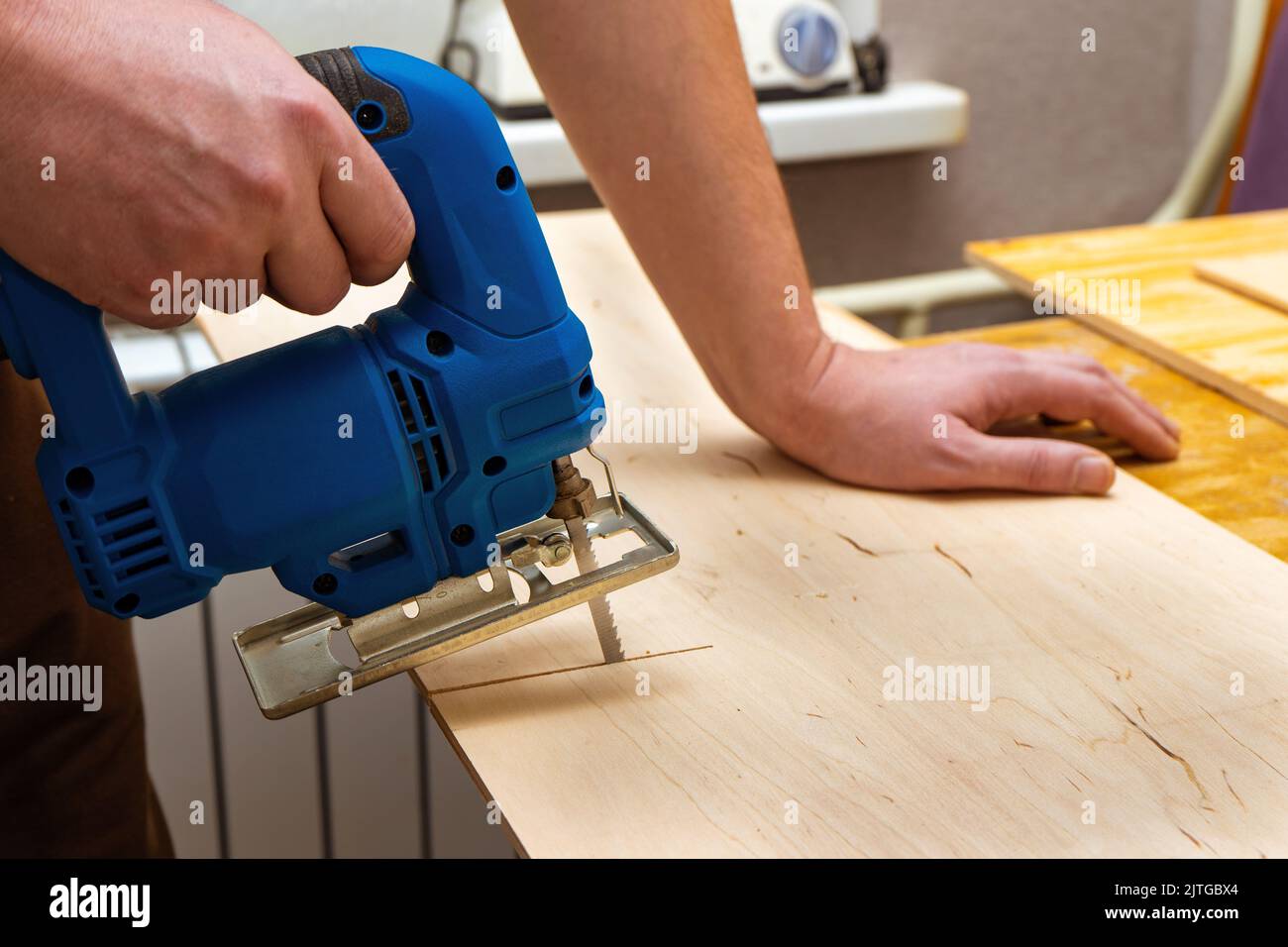 Image of a man hand using electric jigsaw. close up process of cutting