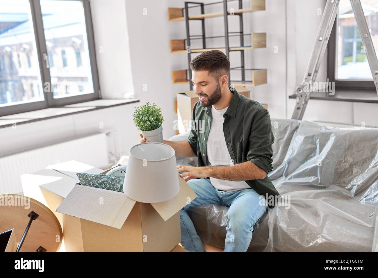 happy man packing boxes and moving to new home Stock Photo - Alamy