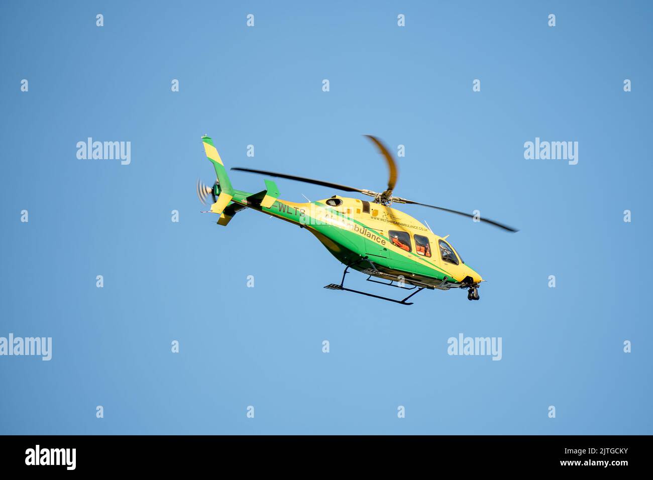 Wiltshire Air Ambulance in flight, clear blue sky Stock Photo