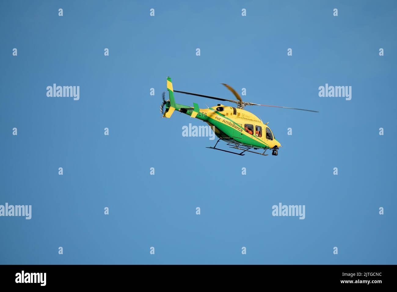 Wiltshire Air Ambulance in flight, clear blue sky Stock Photo