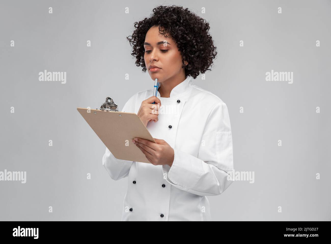 thinking female chef with clipboard and pen Stock Photo