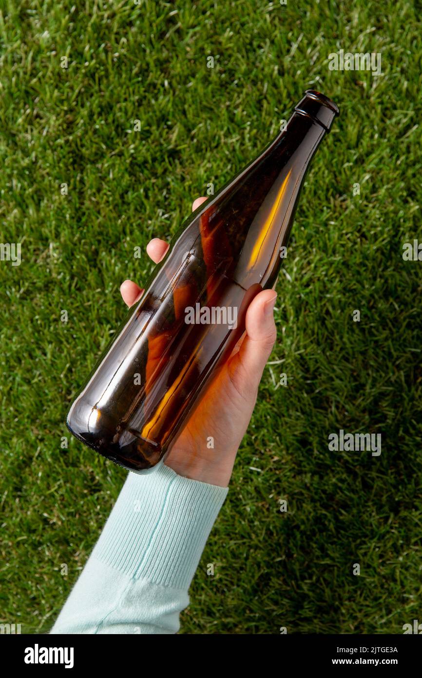 hand removing glass beer bottle from grass Stock Photo Alamy