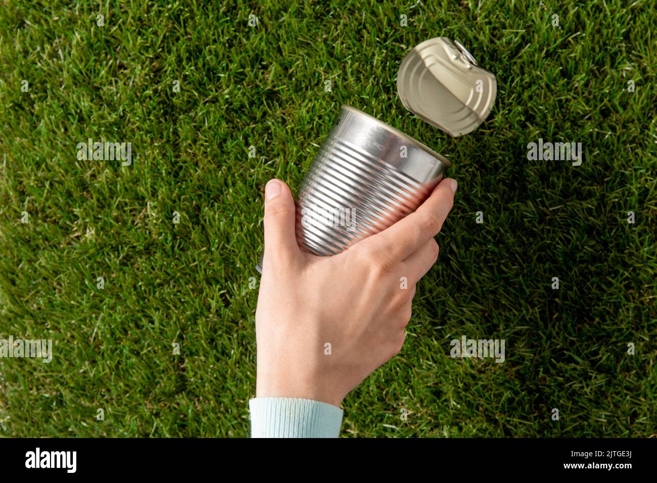 close up of hand removing used tin can from grass Stock Photo Alamy