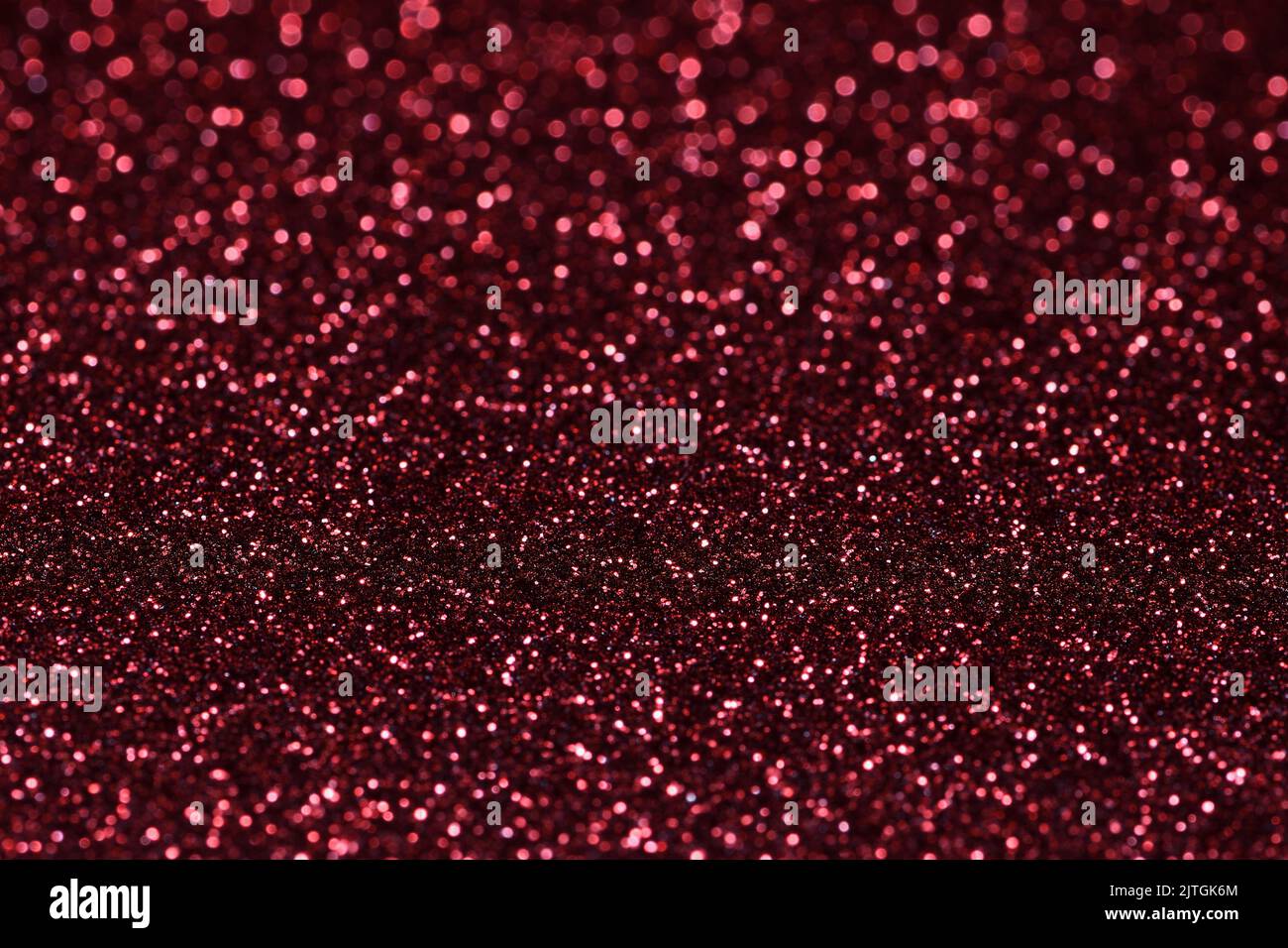 An extreme close-up of a flat piece of sparkly vibrant red coloured craft paper with a very shallow depth-of-field focal point Stock Photo