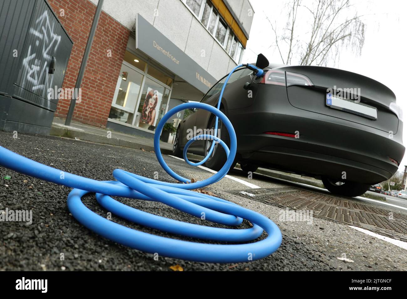 Car at a charging station with blue charge cable, Germany, North Rhine-Westphalia, Cologne Stock Photo