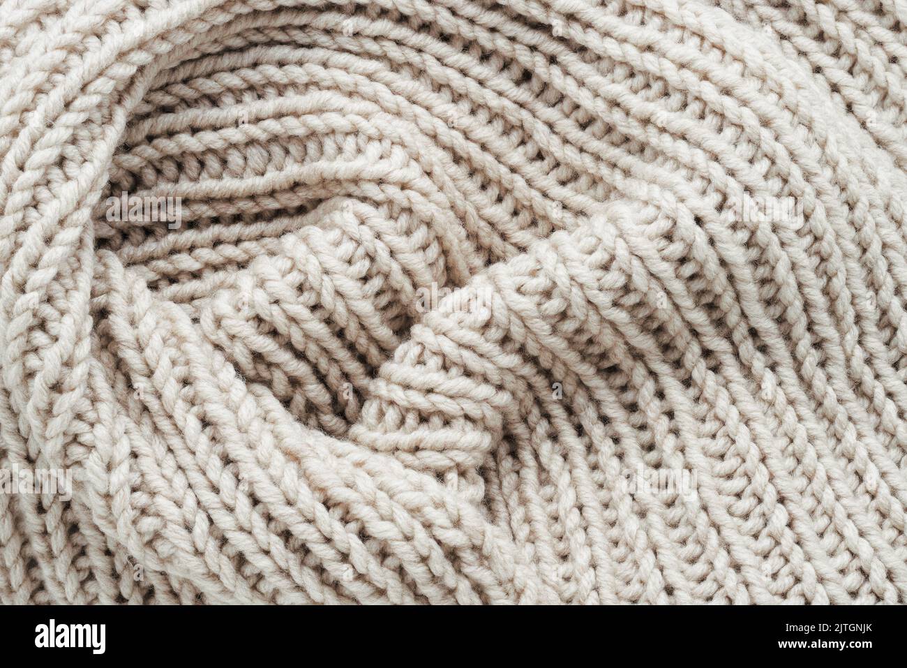 Knitting. Vertical striped beige knit fabric texture, knitted pattern background. Top view. Stock Photo