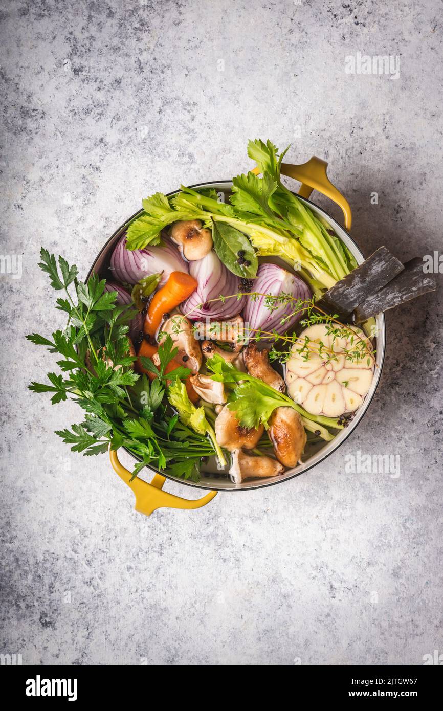 Vegetables and herb ingredients for soup in Dutch oven with light background Stock Photo
