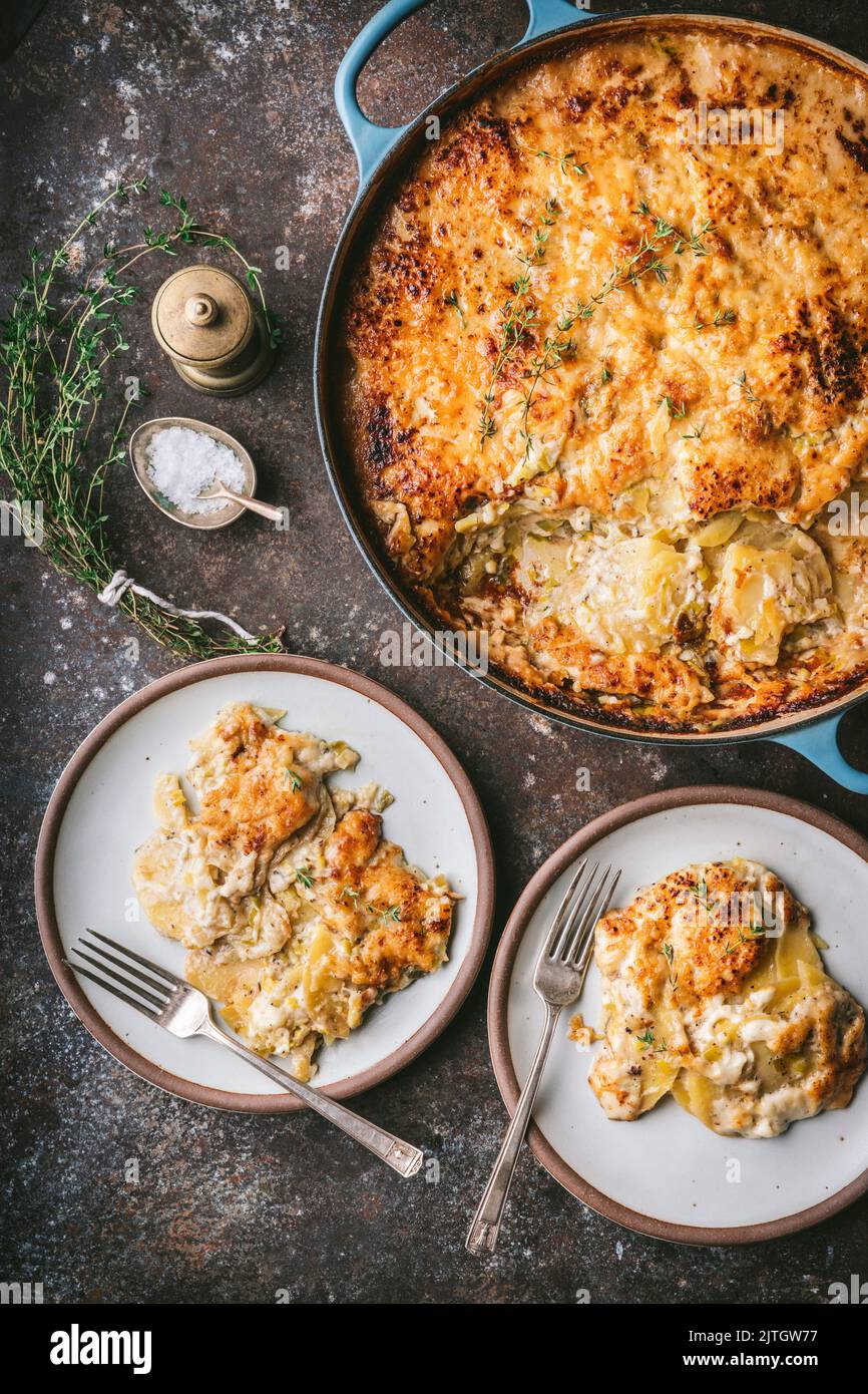 Gratin in Dutch oven with two serving plates Stock Photo Alamy