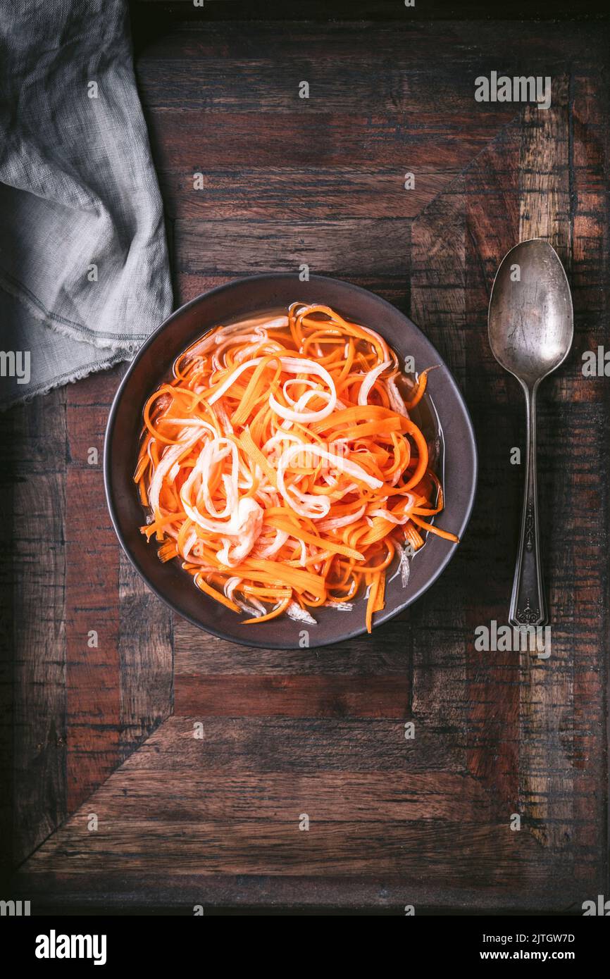 Bowl with Vietnamese Carrot and Daikon Pickles spoon and napkin on wood