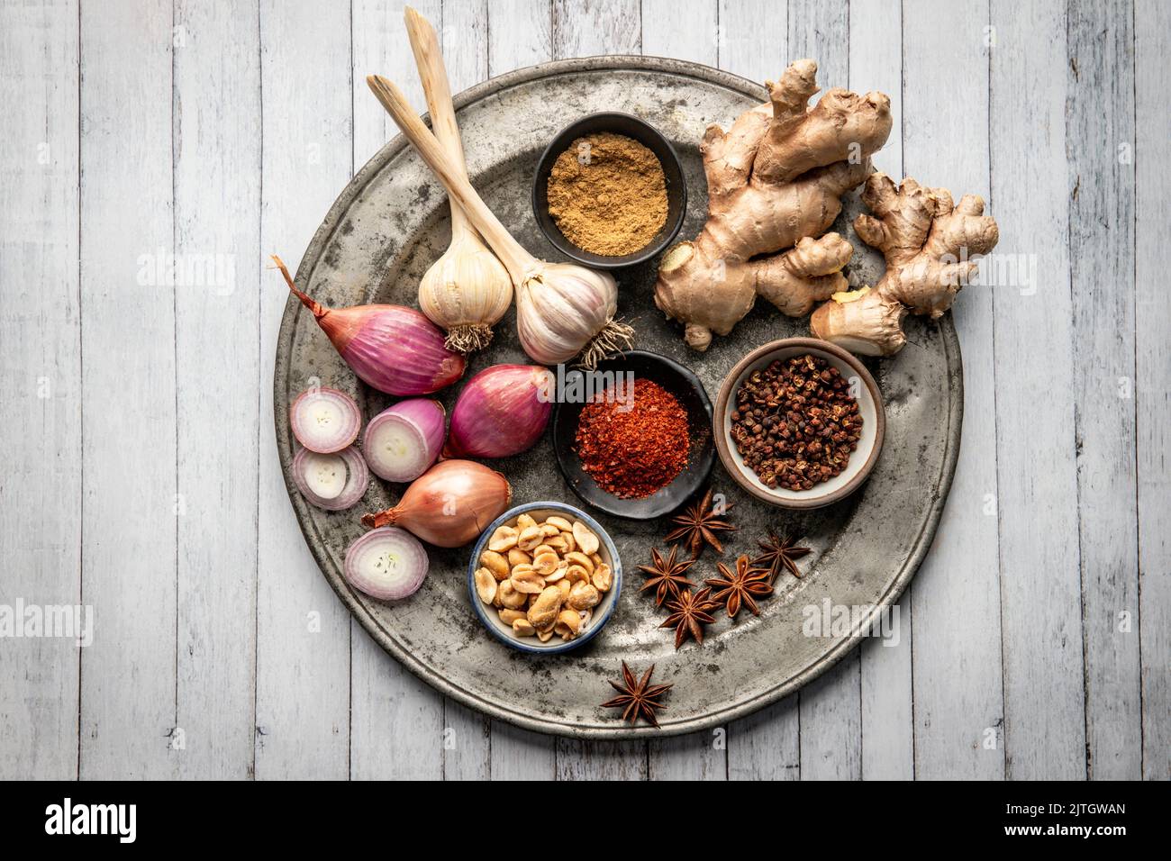 Ingredients for Asian dish arranged on metal plate (garlic, ginger, shallot, chili, star anise) Stock Photo