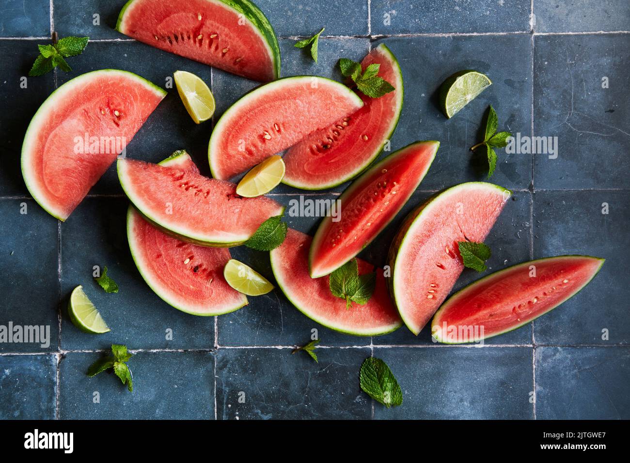 Watermelon slices with mint & lime on blue tiles Stock Photo