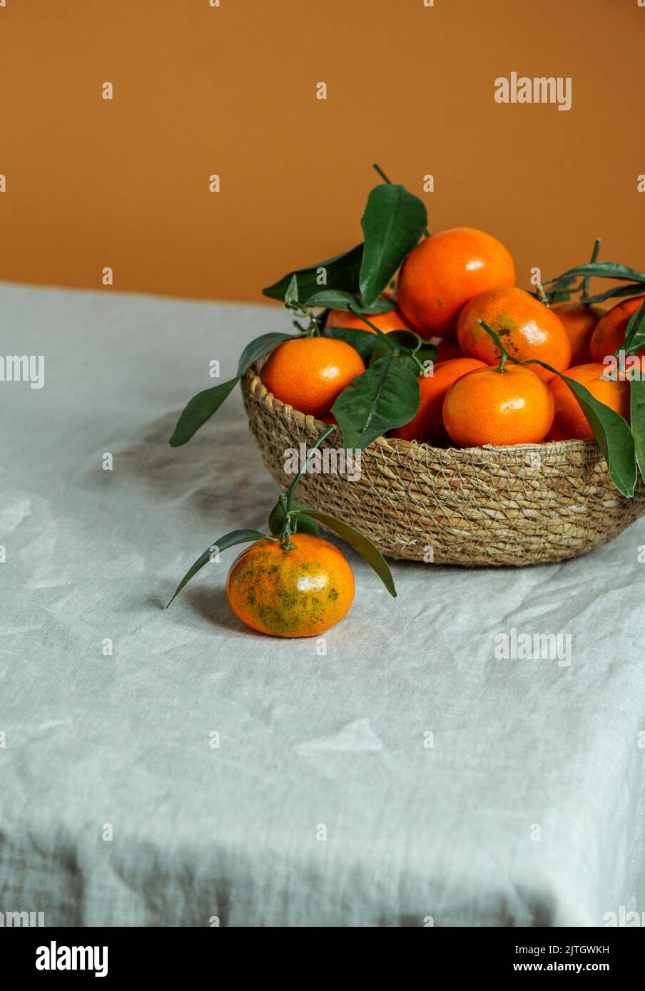 fresh tangerines in a bowl of vines on a linen tablecloth Stock Photo