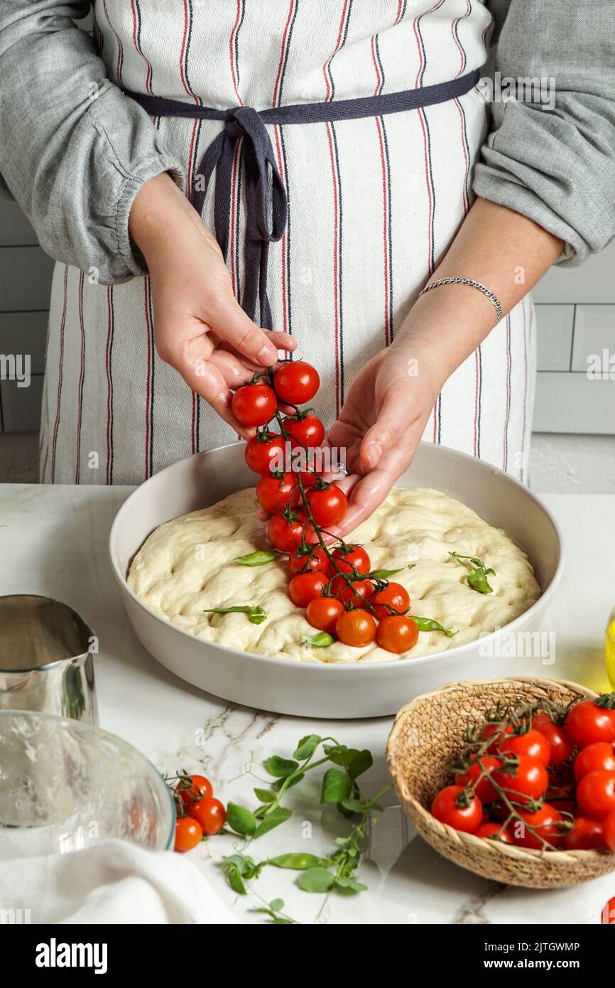 Italian Focaccia with cherry tomatoes, woman preparing process Stock ...