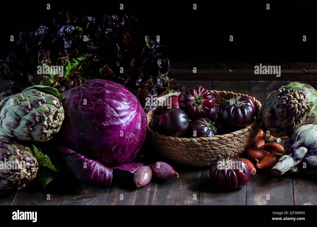 violet vegetables on the wooden background, purple artichoke, tomatoes, oniones, salad Stock Photo