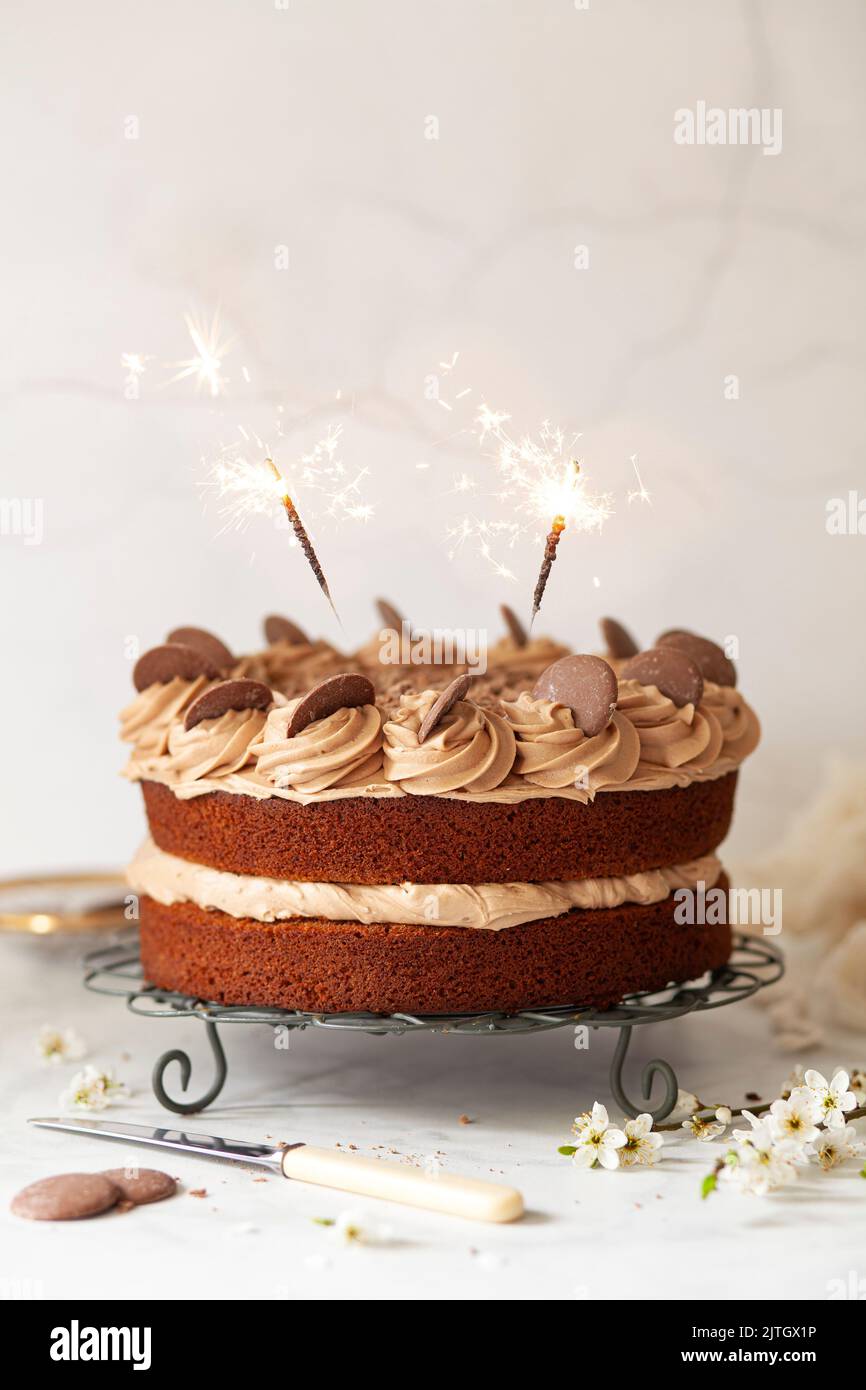 Milk chocolate sponge cake with chocolate buttercream frosting, chocolate buttons and sparklers. Stock Photo