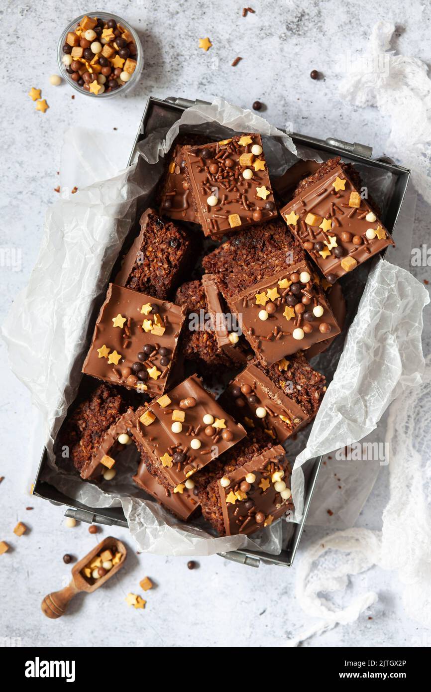 A metal tin holding squares of Australian crunchie chocolate bars that are topped with milk chocolate and mixed sprinkles. Stock Photo