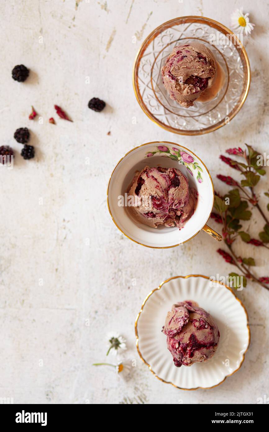 Balls of blackberry ripple and chocolate ice cream in bowls and teacups. Stock Photo