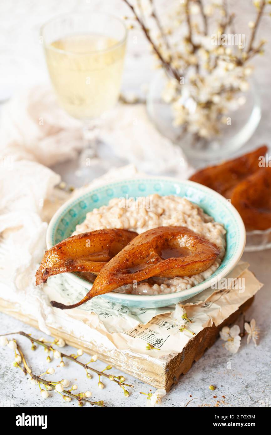 A bowl of rice pudding topped with two pear halves that have been roasted with baking spices. Stock Photo