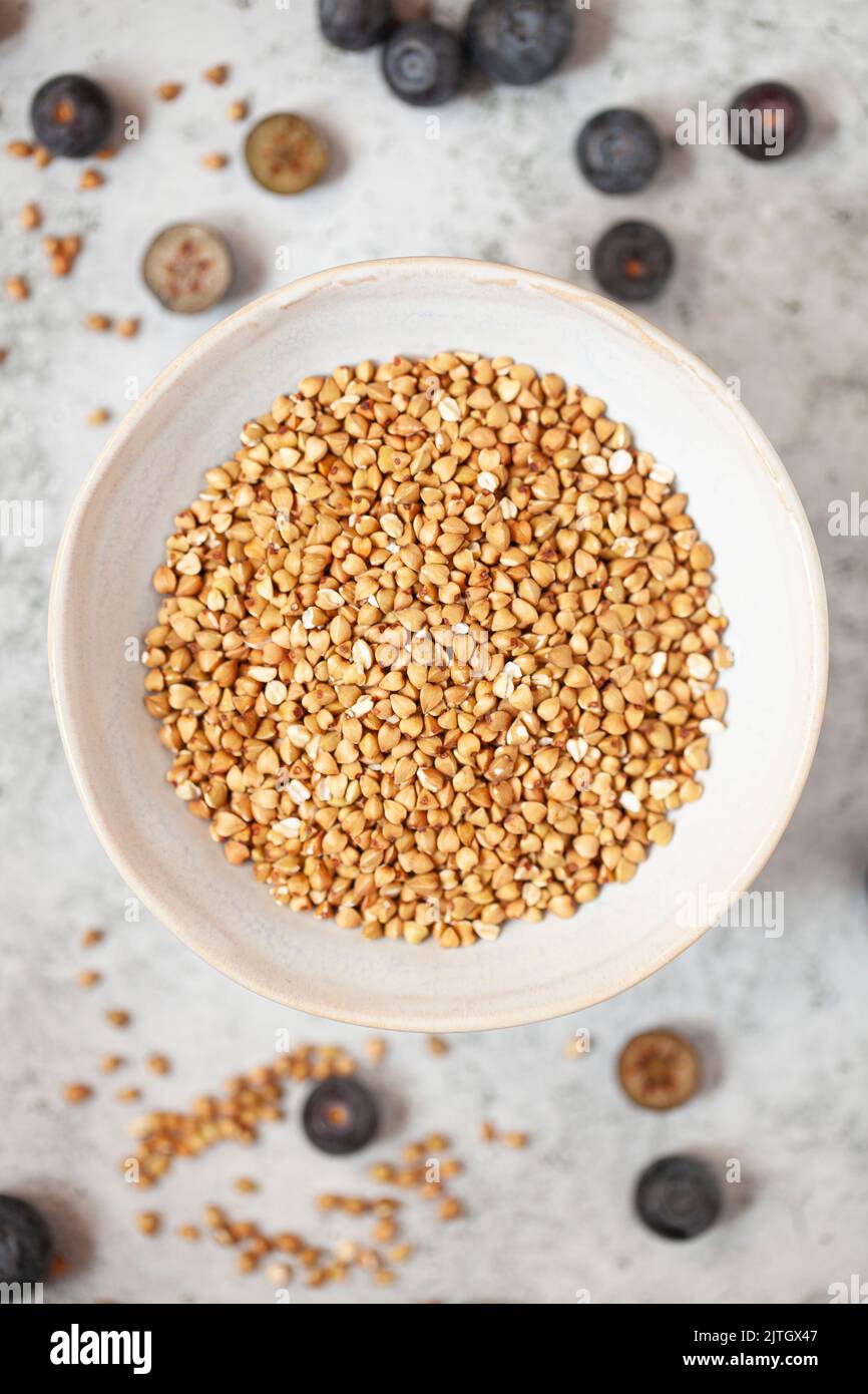 A bowl of buckwheat groats with blueberries on a worktop Stock Photo