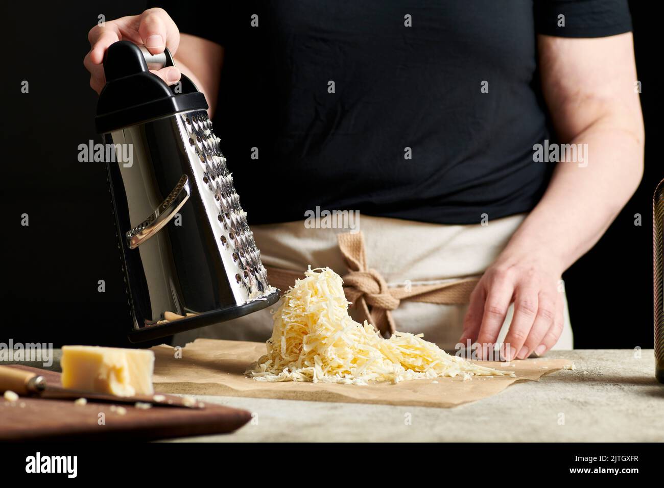 Hands grating cheese onto parchment paper Stock Photo Alamy